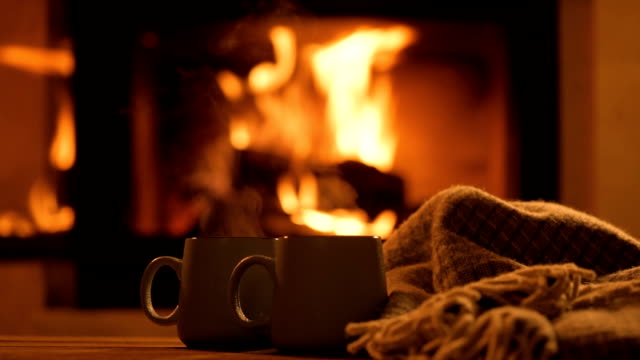 Steam from a cups with a hot cocoa on the fireplace background.