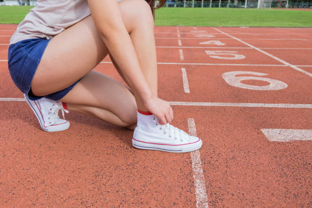 istock Woman runner tying shoelace on running racetrack 908678336