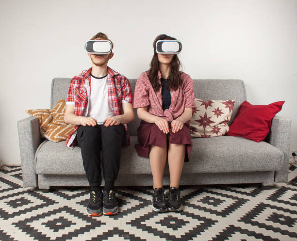 istock young couple in VR glasses sitting on sofa 908682212