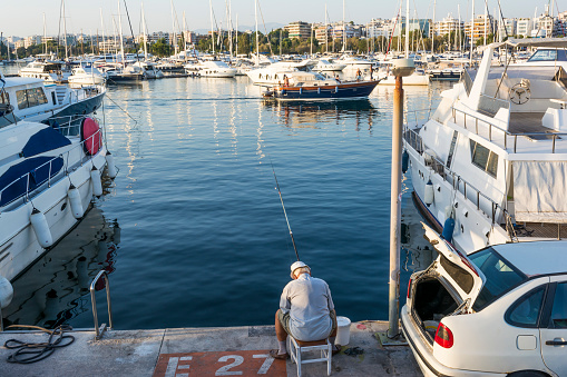 ATHENS, GREECE SEPTEMBER 17 2017: Fisherman among of yachts in Alimos marina in Athens, Greece