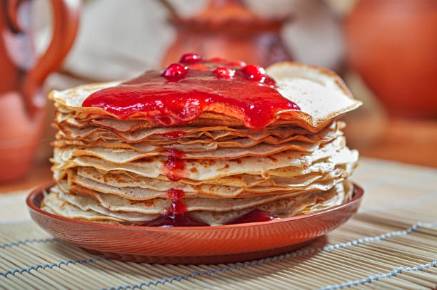 Breakfast with hot pancakes and strawberry ice-cream. Delicate and delicious pancakes on a wooden plate with red jam. High quality photo