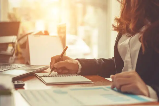 Photo of Business woman at working with financial reports and laptop computer in the office