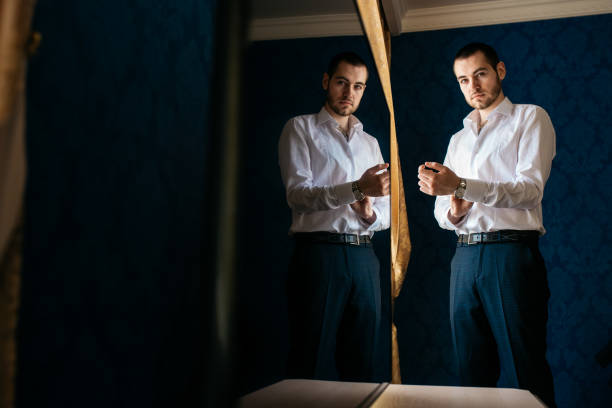 istock A handsome man in a white shirt buttoned his cuffs. Its reflection on the TV screen 908692866