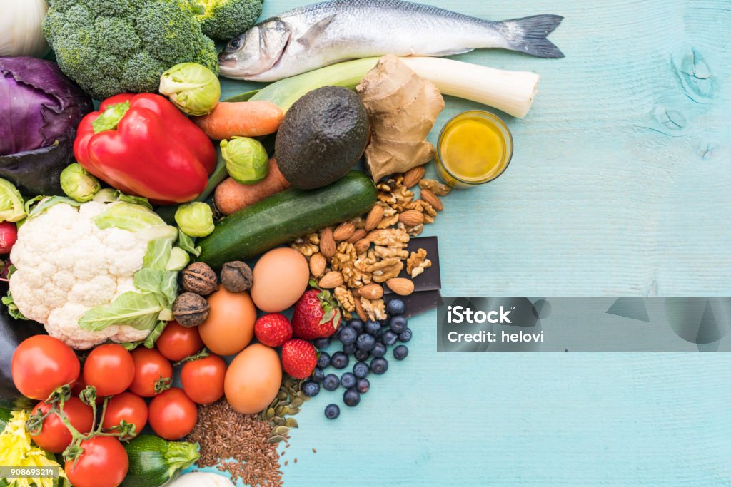 Low carb food Variety of vegetables, seeds, nuts, eg, berries, fish and chocolate on green wooden table. Paleo Diet Stock Photo