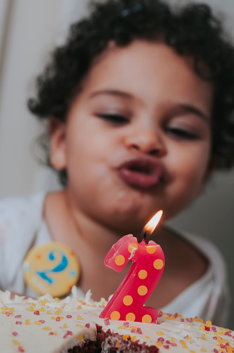 Stock photo of a little girl who is blowing her 2 years old birthday candle.