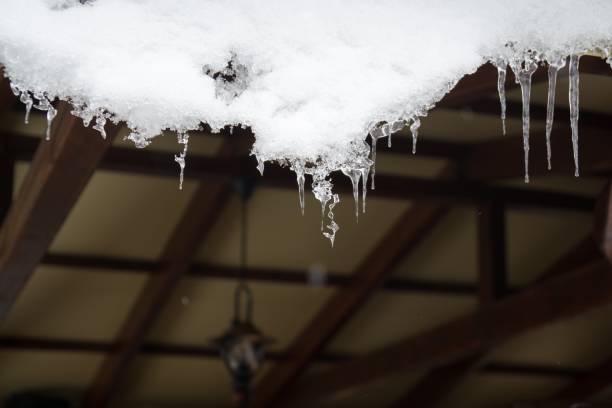 istock Icicles hanging from roof covered by snow in winter. 908702604