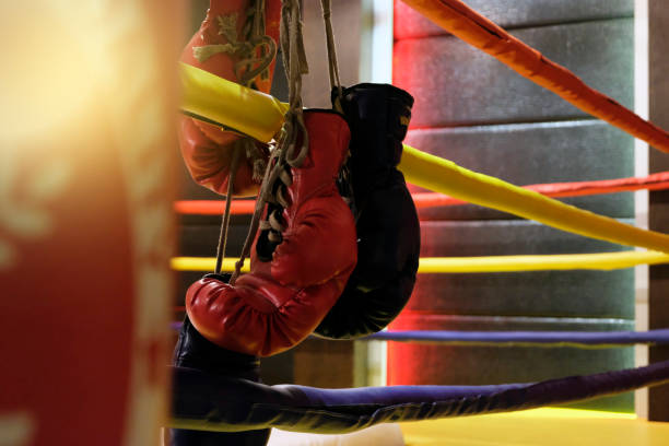 istock Punching bag and red boxing gloves hangs off the boxing ring 908702820