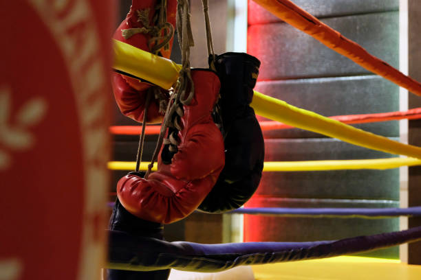 istock Punching bag and red boxing gloves hangs off the boxing ring 908703032