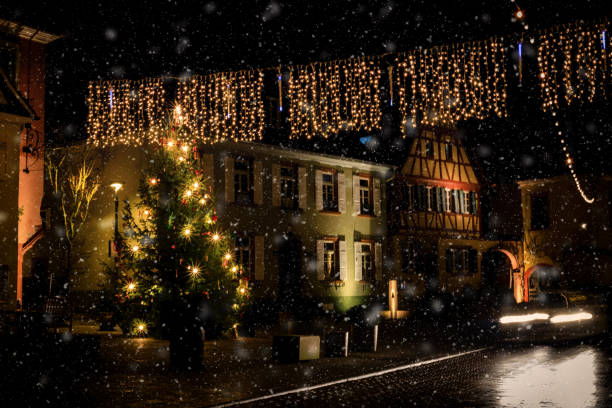 istock Romantic, illuminated Christmas tree during snowfall in the market square of Nierstein with a car rushing by 908710816