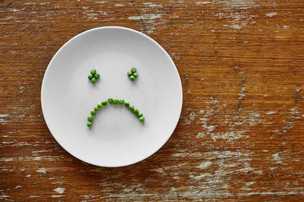 sad hungry smiley face out of peas on plate