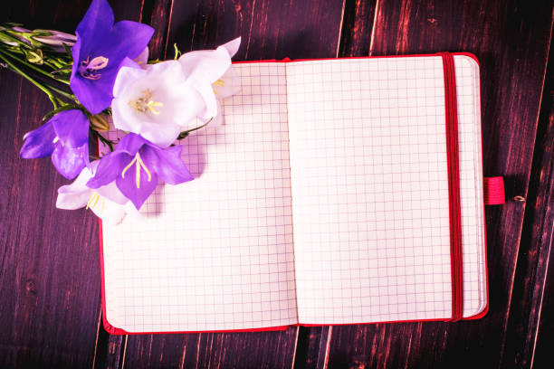 istock blank note book close-up with spring flowers and copy space on wooden background. summer border template. mock-up floral background. sale, greeting and celebration card concept. 908730912