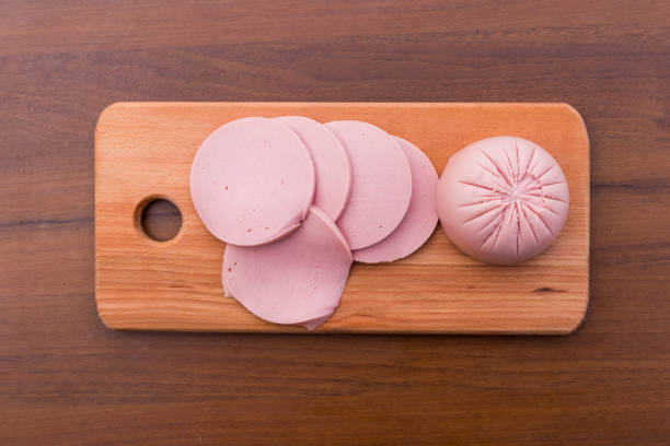 istock Sliced boiled sausage on cutting board on wooden table 908731276