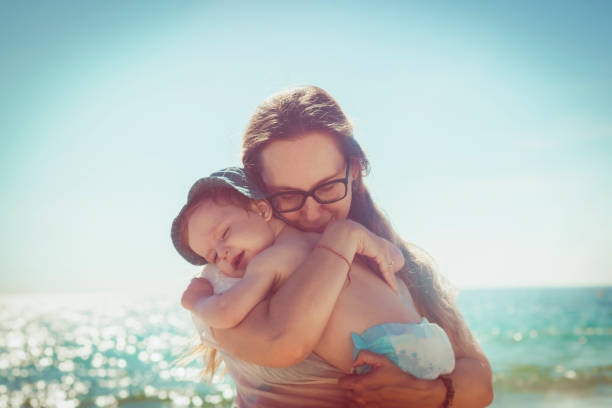Happy mother and her baby boy on the beach in summer