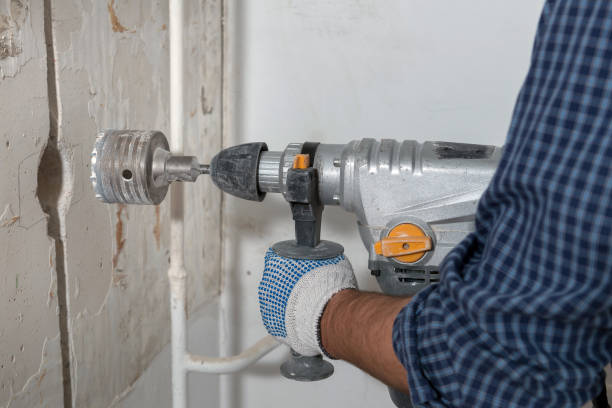 istock Man drilling hole for electrical box in a concrete wall 908734694