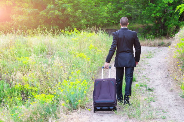 istock A business man in a suit and suitcase in his hands walks along a forest path, free space. 908741338