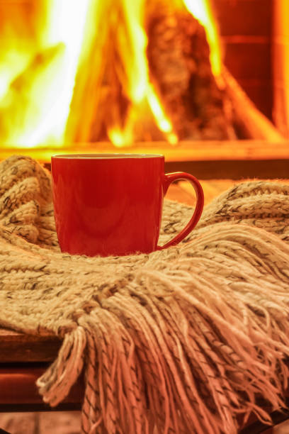 istock Orange mug for tea or coffee, wool things near cozy fireplace, winter vacations, selective focus. 908747746