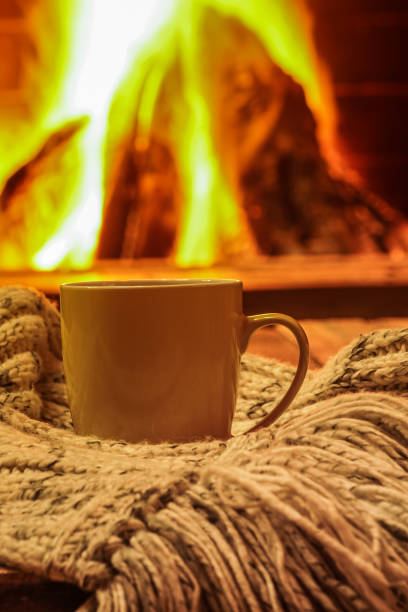 istock Green mug for tea or coffee, wool things near cozy fireplace, winter vacations, selective focus. 908747750
