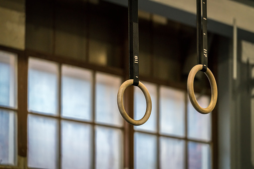 Selective focus of wooden gymnastic rings in front of a large window. Horizontal composition.