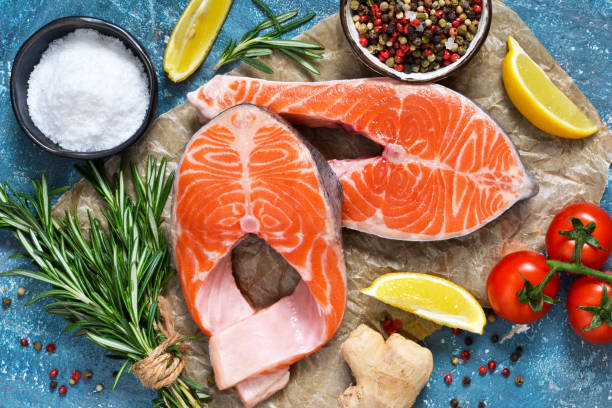 istock Fresh salmon with spices and rosemary on a blue background. 908758546