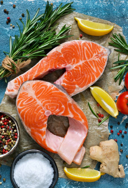 istock Fresh salmon with spices and rosemary on a blue background. 908758574