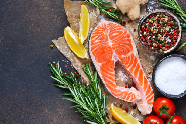 istock Fresh salmon with lemon, salt, spices and rosemary on a concrete background. 908759080