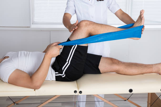 Physiotherapist Helping Patient While Exercising Physiotherapist Helping Patient While Stretching His Leg physical therapy stock pictures, royalty-free photos & images