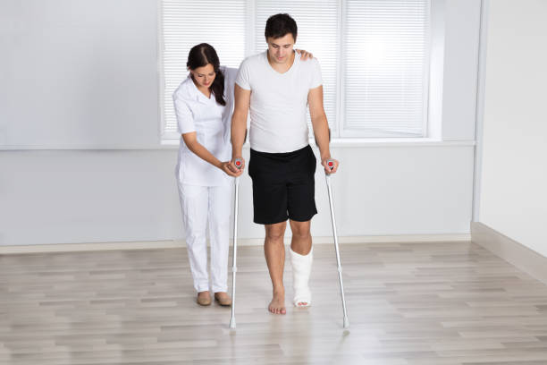 istock Physiotherapist Assisting Injured Patient To Walk With Crutches 908764890