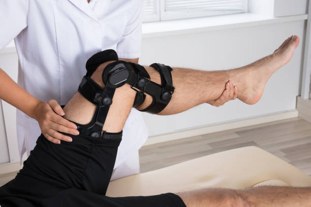 istock Physiotherapist Fixing Knee Braces On Man's Leg 908764902