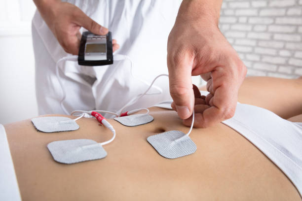 istock Therapist Placing Electrodes On Woman's Stomach 908765090