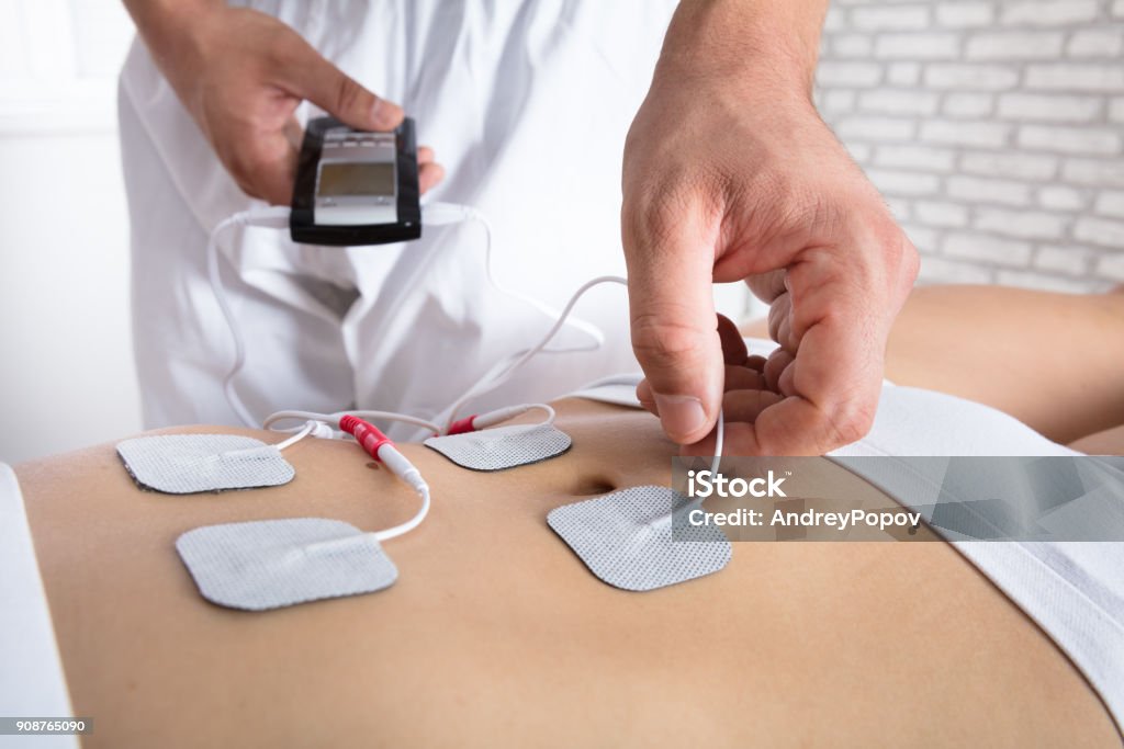 Therapist Placing Electrodes On Woman's Stomach Close-up Of A Therapist's Hand Placing Electrodes On Woman's Stomach Electrode Stock Photo