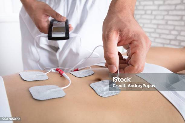 Therapist Placing Electrodes On Womans Stomach Stock Photo - Download Image Now - Electrode, Stomach, Enjoyment