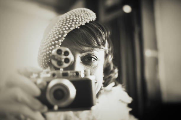 Vintage woman at bar counter making photos with old camera and looking directly into the camera Vintage woman at bar counter making photos with old camera and looking directly into the camera photographic film camera stock pictures, royalty-free photos & images