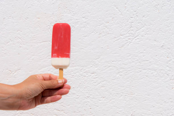 istock Cropped Hand Holding Flavored Ice Against Wall 908770766