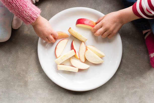 Cropped Hands Of Children Having Apple At Home