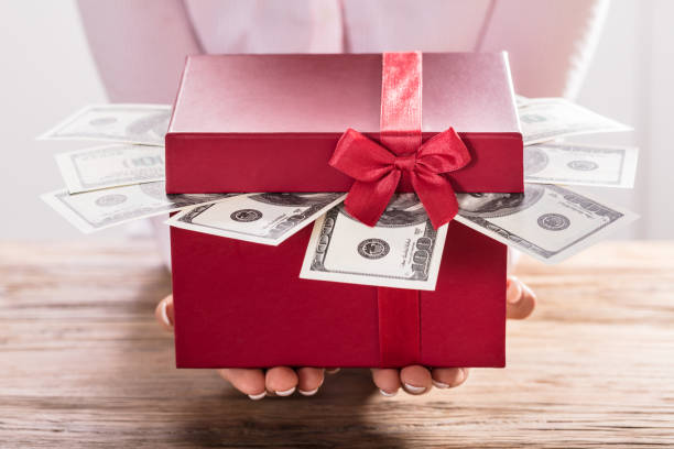 istock Woman Holding Gift Box Of Us Dollar Bills 908787572