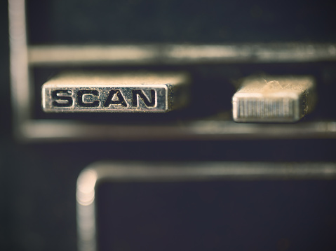Close-up of the Scan push button on an old and dirty car radio.