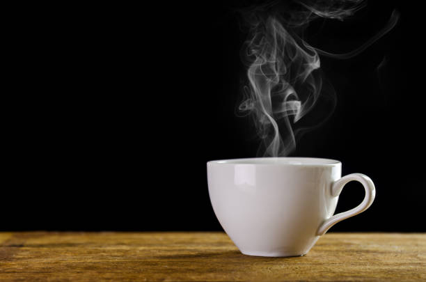 primer plano de la taza de café en la mesa sobre fondo negro - coffee coffee cup steam cup fotografías e imágenes de stock