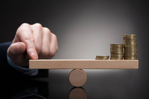istock Finger Balancing Stacked Coins On Seesaw 908800938