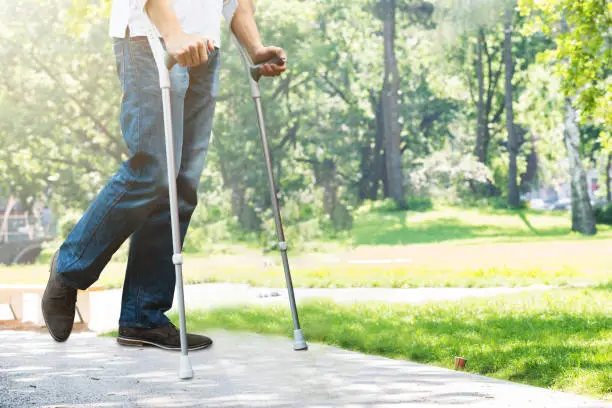 Close-up Of Man Walking With Crutches In Park