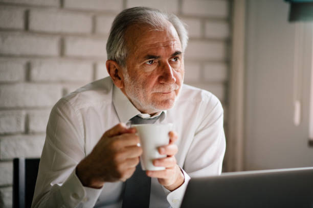 istock Senior retiree drinking tea and working on lap top 908833948