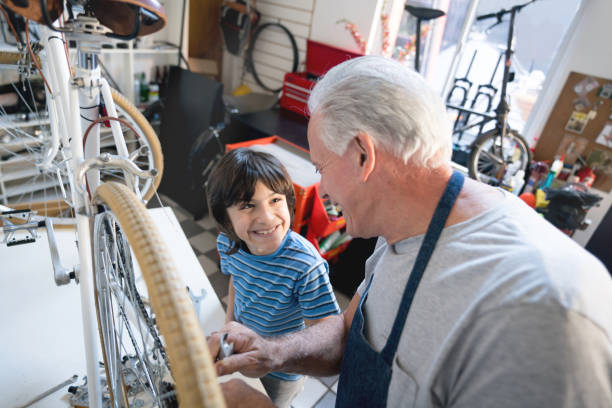 Portrait of happy seven year old boy helping his father repairing car on the pavement at sunny day