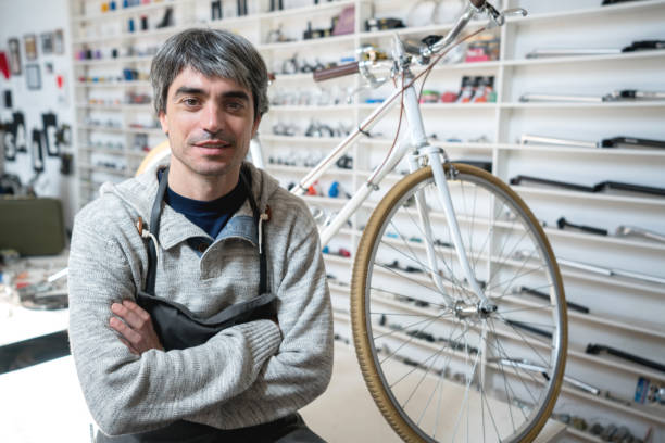 istock Business owner of a bicycle store sitting on table looking at camera smiling 908850332