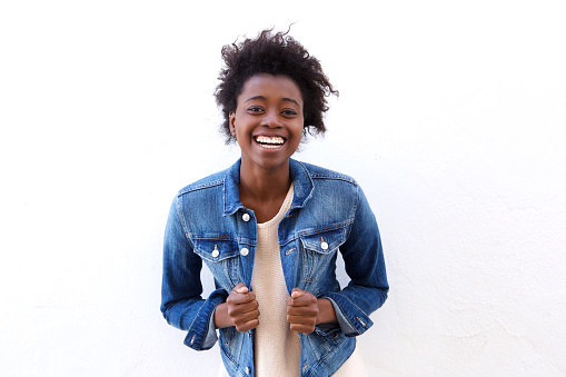 Portrait of young african american woman laughing with jeans jacket against white background