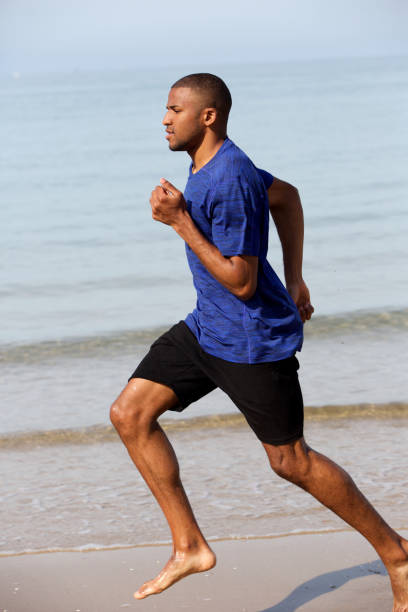 istock Young african man running along the beach 908851038