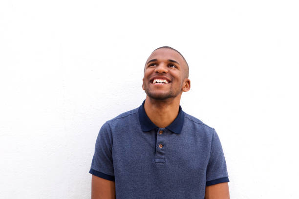istock Young black man looking up against white background 908851152