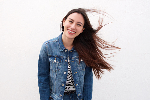 Portrait of happy woman in denim jacket with long hair blowing