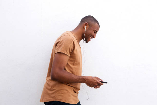 istock Young black man enjoying music on mobile phone against white background 908851254