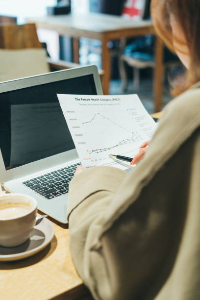 istock woman doing paperwork with laptop in coffee shop 908874644