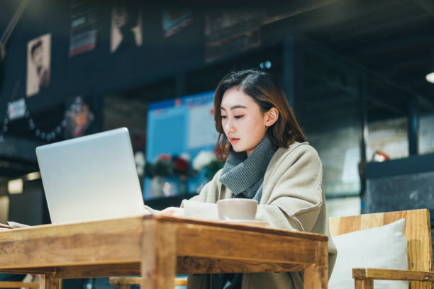 istock woman doing paperwork with laptop in coffee shop 908884412
