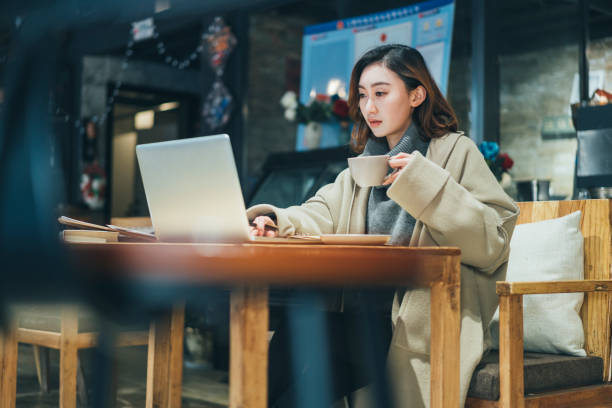 istock woman doing paperwork with laptop in coffee shop 908884488
